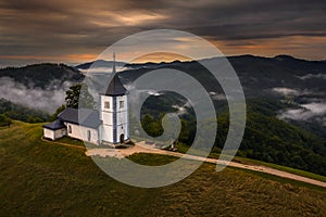 Jamnik, Slovenia - Aerial drone view of a golden sumer sunrise at Jamnik St.Primoz church