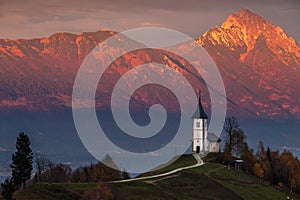 Jamnik, Slovenia - Beautiful golden sunset at Jamnik St. Primoz church with Julian Alps at background photo