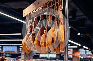 Jamon hangs on a crossbar in a supermarket. Blurred background