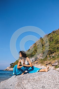 Jana shirshasana on a rock early morning near the sea