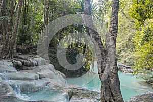 Jangle landscape with flowing turquoise water of Erawan cascade waterfall