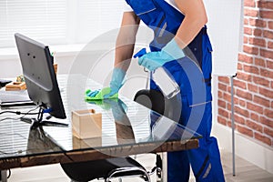 Janitor Cleaning Desk With Cloth In Office