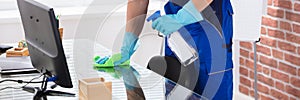 Janitor Cleaning Desk With Cloth In Office