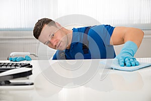 Janitor Cleaning Desk With Sponge At Office