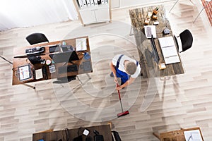 Janitor Cleaning Floor With Broom In Office