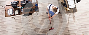 Janitor Cleaning Floor With Broom In Office