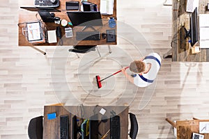 Janitor Cleaning Floor With Broom In Office