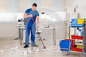 Janitor Cleaning Floor With Broom In Office