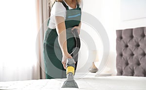 Janitor cleaning mattress with professional equipment in bedroom,