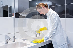 Janitor cleaning sink in public washroom photo