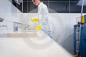 Janitor cleaning sink in public washroom photo