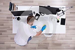 Janitor cleaning white desk in office