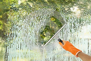 Janitor cleaning window with squeegee indoors