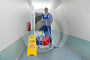 Janitor Holding Mop With Bucket And Wet Floor Sign