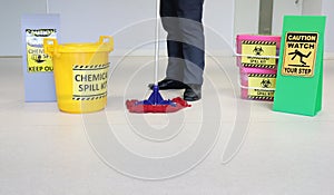 Janitor male cleaning floor in medical service room or laboratory with caution tag sign watch your step and Biohazard spill kit, c