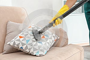 Janitor removing dirt from sofa cushion with steam cleaner