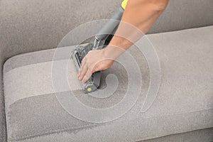 Janitor removing dirt from sofa with upholstery cleaner