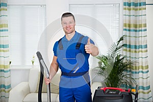 Janitor Showing Thumbs Up While Holding Vacuum Cleaner At Home