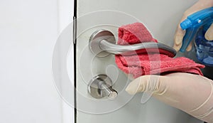 Janitor wear surgical gloves cleaning the door handles with an antiseptic alcohol sanitizer during a viral epidemic corona virus photo