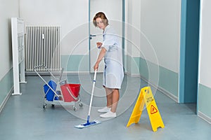 Janitor With Wet Caution Sign And Cleaning Equipments
