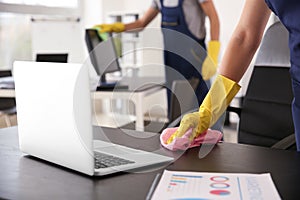 Janitor wiping table in office