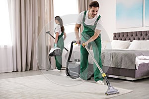 Janitors cleaning bedroom with professional equipment