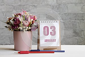 january 03. 03-th day of the month, calendar date.A delicate bouquet of flowers in a pink vase, two pencils and a