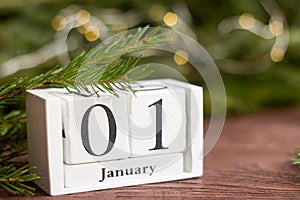 January 1 on the calendar on a wooden background next to the Christmas tree.The concept of the beginning of the new year