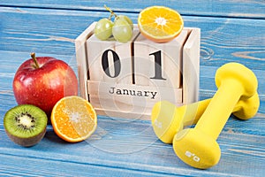 January 1 on cube calendar, fruits and dumbbells, new years resolutions concept