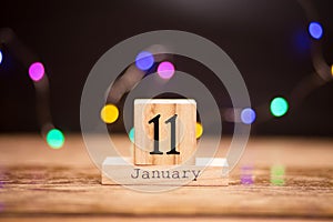 January 11th. Day 11 of month, calendar on dark background with garland bokeh. Winter time