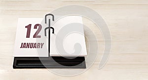 january 12. 12th day of month, calendar date. Stand for desktop calendar on beige wooden background. Concept of day of