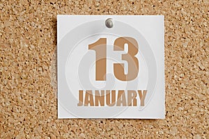 january 13. 13th day of the month, calendar date.White calendar sheet attached to brown cork board.Winter month, day of