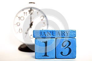 january 13th. Day 13 of month, handmade wood calendar and alarm clock on blue color. winter month, day of the year concept