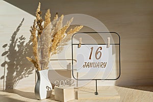 january 16. 16th day of month, calendar date. White vase with dead wood next to the numbers 2022 and stand with an empty