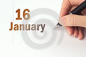 January 16th. Day 16 of month, Calendar date. The hand holds a black pen and writes the calendar date. Winter month, day of the