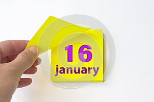 January 16th. Day 16 of month, Calendar date. Hand rips off the yellow sheet of the calendar. Winter month, day of the year