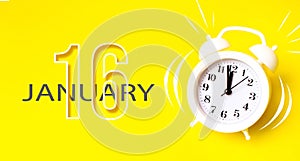 January 16th. Day 16 of month, Calendar date. White alarm clock with calendar day on yellow background. Minimalistic concept of