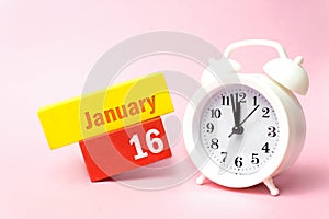 January 16th. Day 16 of month, Calendar date.White alarm clock on pastel pink background. Winter month, day of the year concept