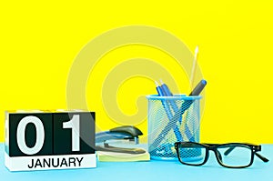 January 1st. Day 1 of january month, calendar on yellow background with office supplies. Winter time