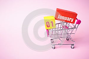 January 1st . Day 1 of month, Calendar date. Close up toy metal shopping cart with red and yellow box inside with Calendar date on