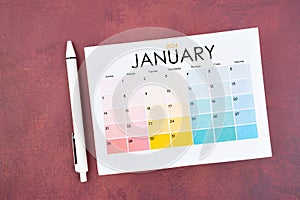 January 2024 calendar page and pen on red color background