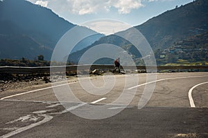 January 21st 2022 uttarakhand India. A traveller with backpack walking on an empty asphalt road with mountains on the background