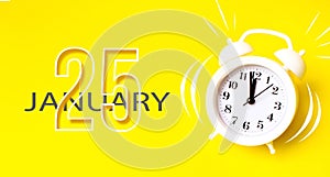 January 25th. Day 25 of month, Calendar date. White alarm clock with calendar day on yellow background. Minimalistic concept of