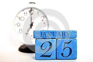 january 25th. Day 25 of month, handmade wood calendar and alarm clock on blue color. winter month, day of the year concept