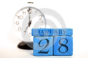 january 28th. Day 28 of month, handmade wood calendar and alarm clock on blue color. winter month, day of the year concept