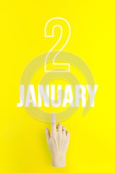 January 2nd. Day 2 of month, Calendar date.Hand finger pointing at a calendar date on yellow background.Winter month, day of the