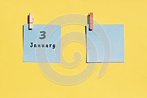 January 3rd. 3rd day of the month, calendar date. Two blue sheets for writing on a yellow background. Top view, copy space. Winter