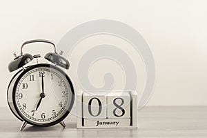 January 8 on a white calendar, next to a retro alarm clock on a light background.Calendar for January.Copy of the space