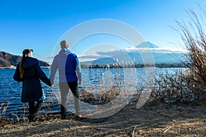 Japan - A couple holding hands at the side of Kawaguchiko Lake and admiring Mt Fuji