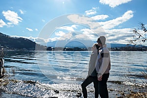 Japan - A couple standing at the side of Kawaguchiko Lake and admire Mt Fuji